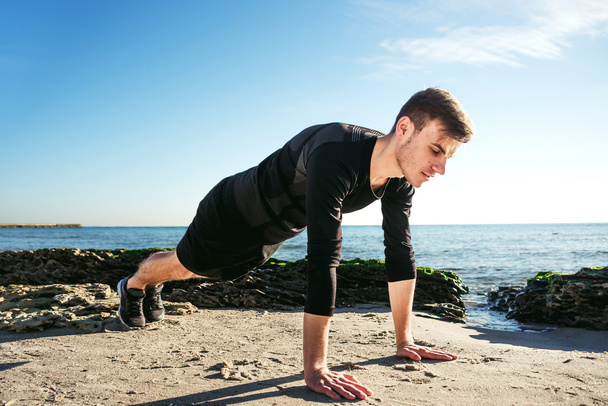 junger Mann trainiert am Strand, sportlicher Mann macht Übungen - Foto, Bild