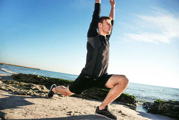 young male working out on beach, sporty man doing exercises - Foto, Imagen
