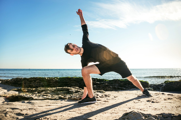 young male working out on beach, sporty man doing exercises - Photo, Image