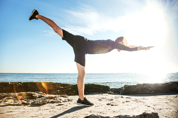 young male working out on beach, sporty man doing exercises - Foto, Bild