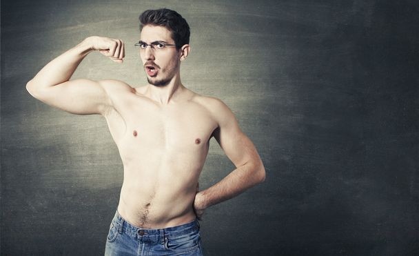Hemdloses männliches Model posiert mit Brille vor grauem Hintergrund mit Muskeln - Foto, Bild