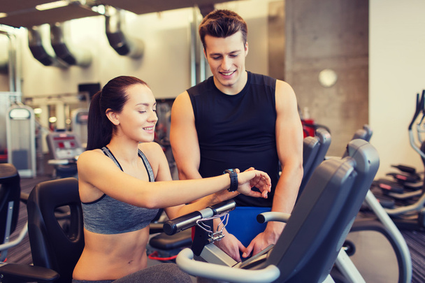 happy woman with trainer on exercise bike in gym - Foto, Imagen