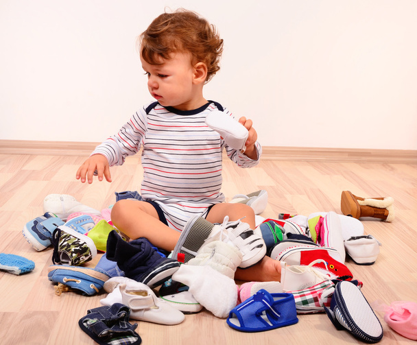 Toddler playing with a lot of baby shoes. - Foto, immagini