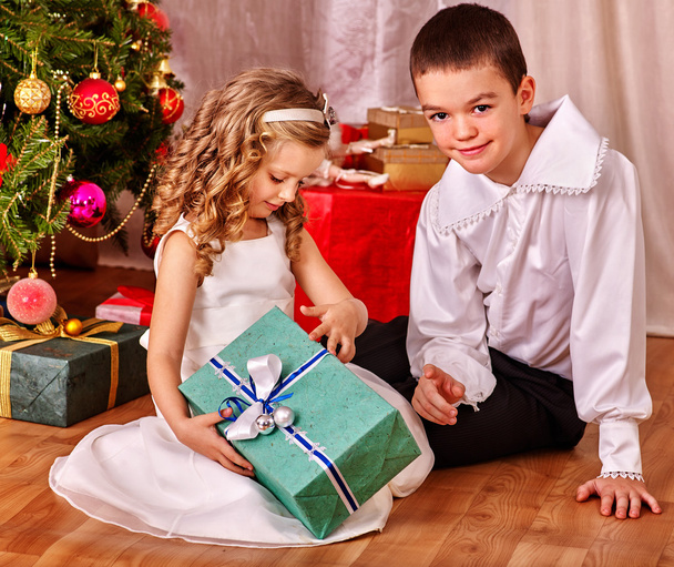 Kinder bekommen Geschenke unterm Weihnachtsbaum. - Foto, Bild
