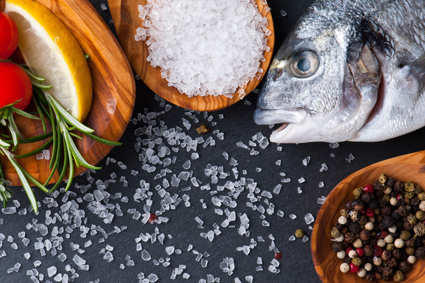 fresh  raw  dorado  fish  with  spices  and herbs on black background, top view - Zdjęcie, obraz