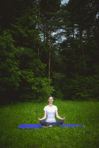Молода красива жінка займається медитацією йоги в лісі на відкритому повітрі
 - Фото, зображення