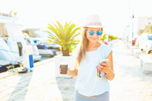 Trendy woman drinking takeaway coffee and walking on the waterfr - Zdjęcie, obraz