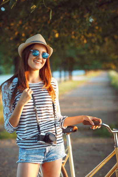 Preciosa joven en un sombrero montando una bicicleta en un parque
 - Foto, Imagen