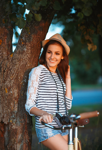 Прекрасна молода жінка в капелюсі з велосипедом в парку
 - Фото, зображення