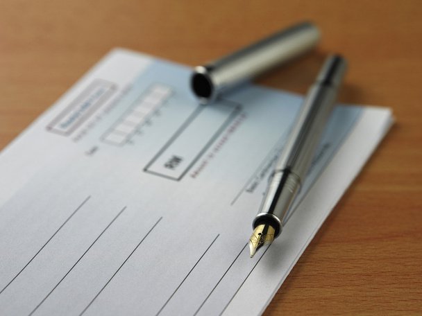 白い背景の上の小切手帳のペンのクローズ アップ - 写真・画像