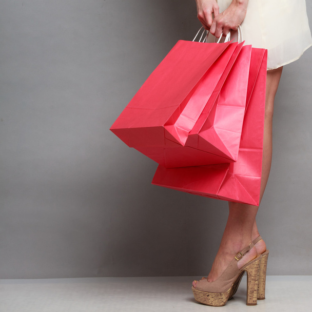 Woman holding red paper shopping bags - 写真・画像