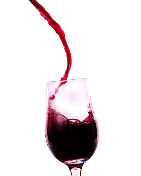 rode wijn stroomt in het glas - Foto, afbeelding