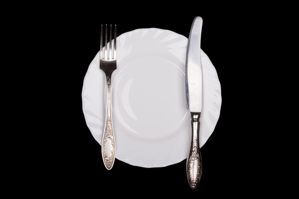Segno di etichetta. Piastra, forchetta, coltello vista dall'alto isolato su nero
 - Foto, immagini