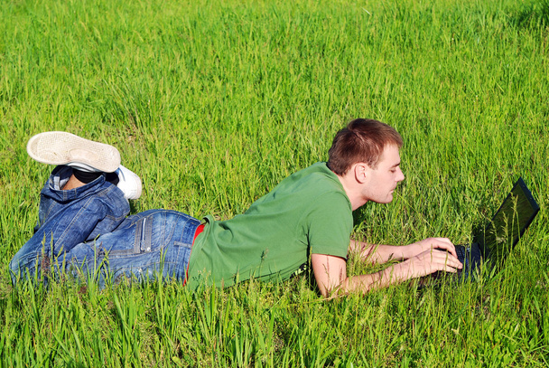 Nuori mies ulkona kannettavan tietokoneen kanssa
 - Valokuva, kuva