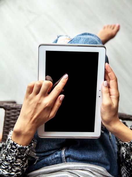 woman holding and using tablet with empty screen, ripped jeans - Foto, imagen