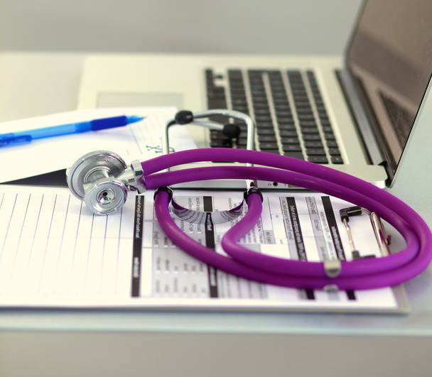 egy orvosi sztetoszkóppal közelében egy laptop, egy fából készült asztal, fehér - Fotó, kép
