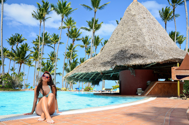 Beautiful woman enjoying her tropical vacantion near the pool - Photo, Image