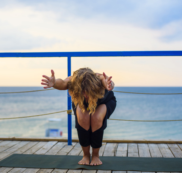young caucasian female practicing yoga on the seaside during the sunrise - Foto, Imagem