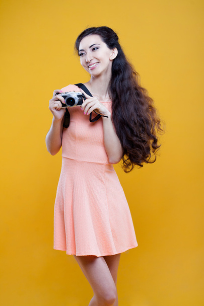 Fashion asian young  girl  photographer with camera, portrait on yellow background - Zdjęcie, obraz