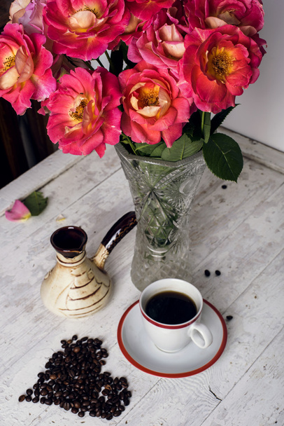 coffee cup, coffee beans and roses on wooden background - Fotoğraf, Görsel