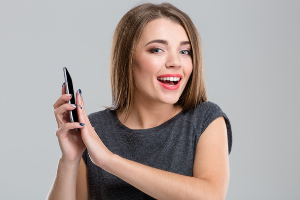 Cheerful woman covering microphone on smartphone - Фото, изображение