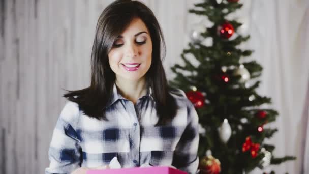 Hermosa mujer joven festiva desenvolviendo regalo de Navidad
 - Metraje, vídeo