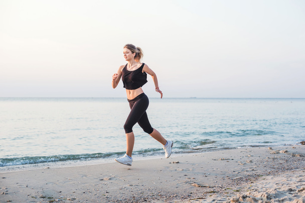 Running woman. Female runner jogging during the sunrise on beach. - Photo, image
