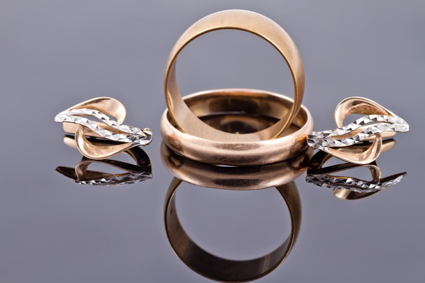 金の結婚指輪と金のイヤリング - 写真・画像