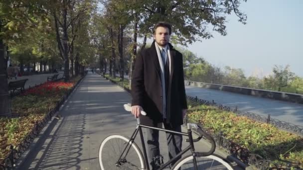 fiatal üzletember állva a város sikátorban a kerékpár - Felvétel, videó