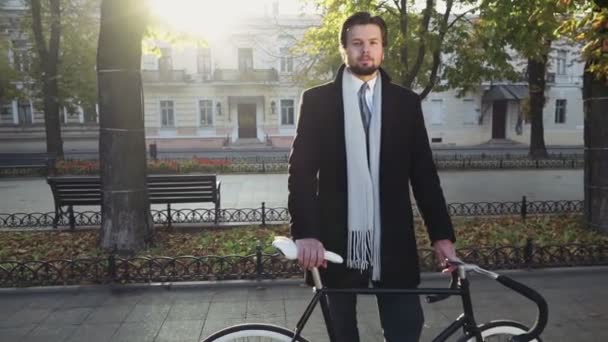 portrait of businessman standing near his bike on autumn boulevard - Filmati, video