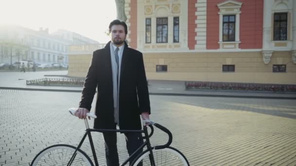 красивый бизнесмен, стоящий на площади рядом с велосипедом
 - Кадры, видео