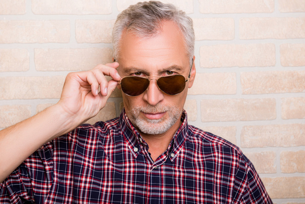 Portrait of handsome old man holding sunglasses - Zdjęcie, obraz