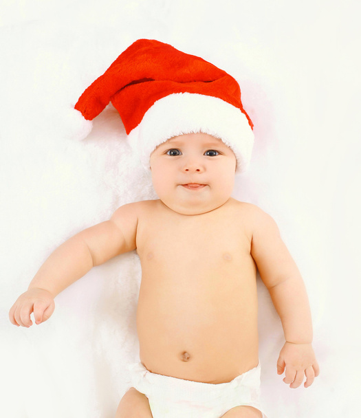 Christmas and family concept - cute baby in red santa hat lying - Foto, immagini