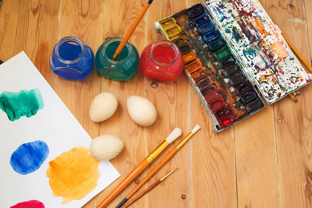 watercolor paints, easter eggs and brushes on the table in the artist's studio. Painting on eggs - Photo, image