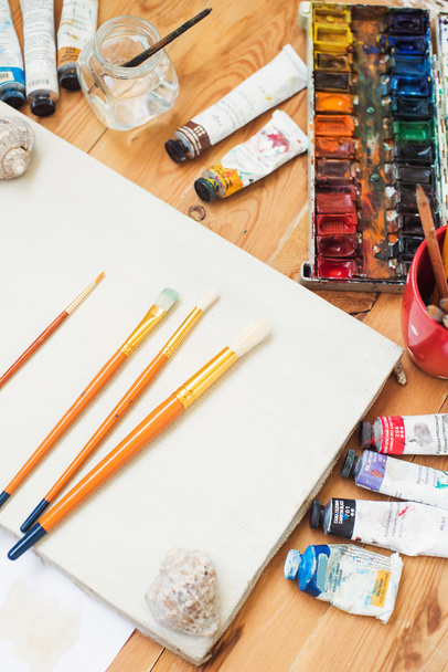 watercolor paints,oil paints, cellphone, glasses and brushes on the table in the artist's studio. - Zdjęcie, obraz