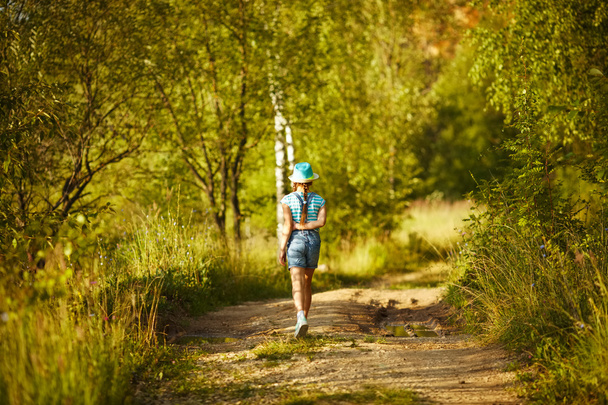 Girl in a hat walks through the birch forest - Foto, imagen