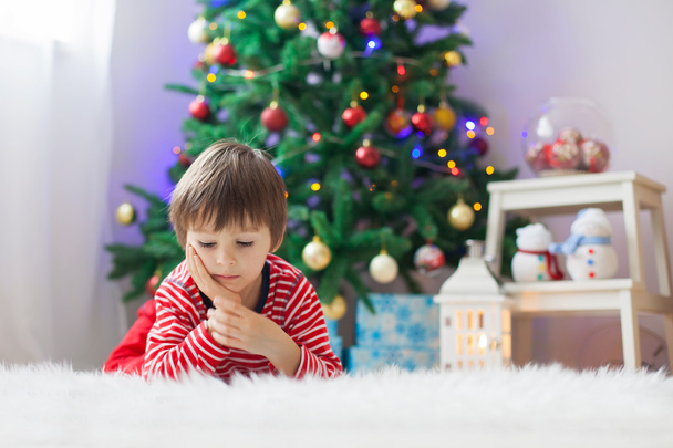 Cute boy, reading a book in front of Christmas tree - Foto, imagen