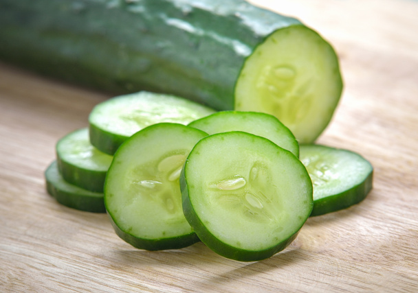 Verse plakjes komkommer op hout achtergrond - Foto, afbeelding