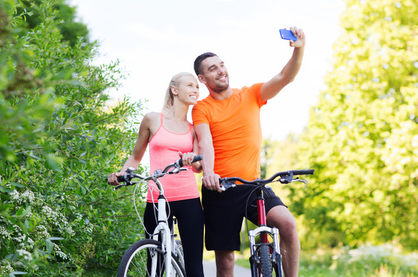 スマート フォンで selfie を取る自転車をカップルします。 - 写真・画像