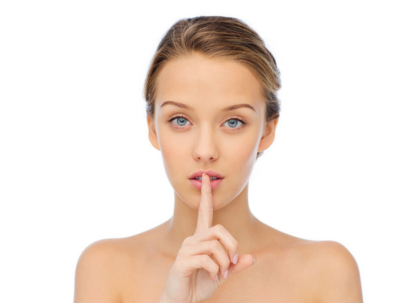 beautiful young woman holding finger on lips - 写真・画像
