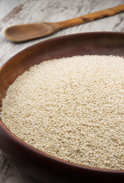 Sesame seeds in a wooden plate over wooden background - Photo, image