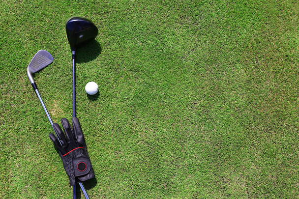 Golf clubs with ball and black glove on a green grass, close up - Fotó, kép