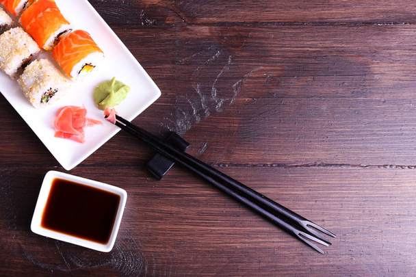 Delicious rolls, ginger, wasabi and soy sauce on wooden background - Foto, Bild