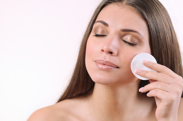 piękna młoda kobieta czyszczenia jej skóra na białym tle - Zdjęcie, obraz