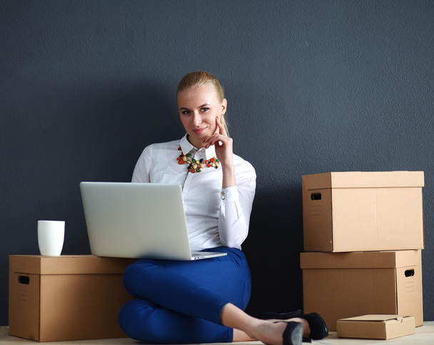 Woman sitting on the floor near a boxes  with laptop - Foto, Bild