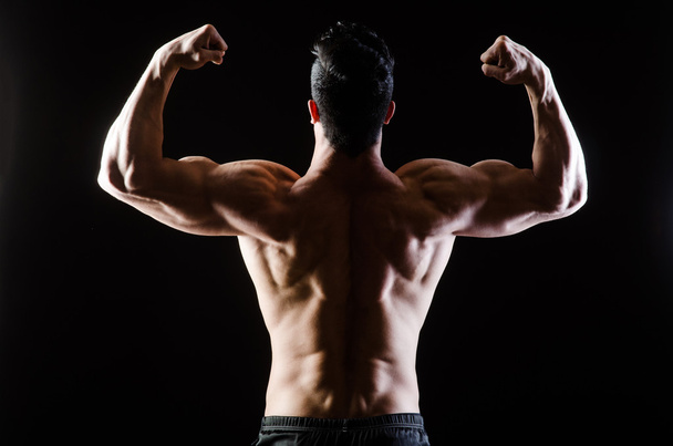 Muscular man posing in dark studio - Photo, Image