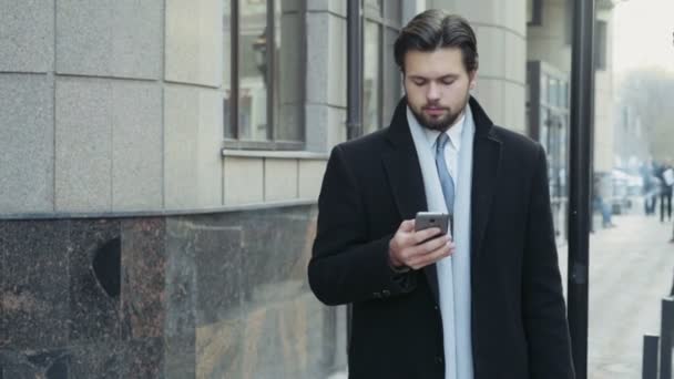 schöner Geschäftsmann, der eine Nachricht in der Innenstadt verschickt - Filmmaterial, Video
