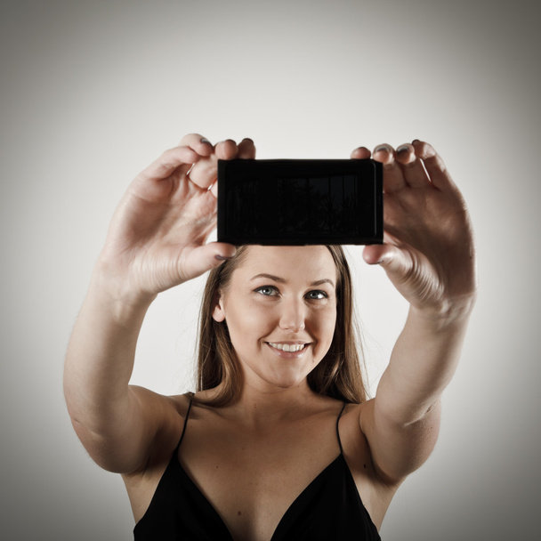 Selfie. Woman taking a selfie using her smartphone. - Foto, Imagem