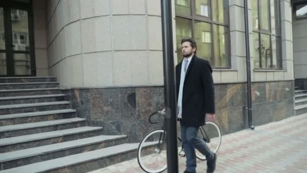 komea liikemies kävelee polkupyörän kanssa keskustassa
 - Materiaali, video