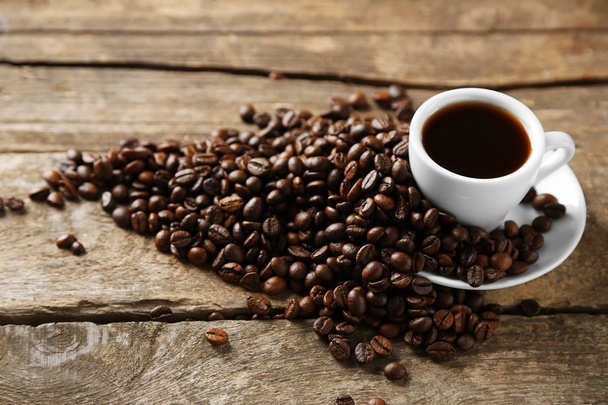 Cup of coffee and coffee grains on wooden background - Fotó, kép